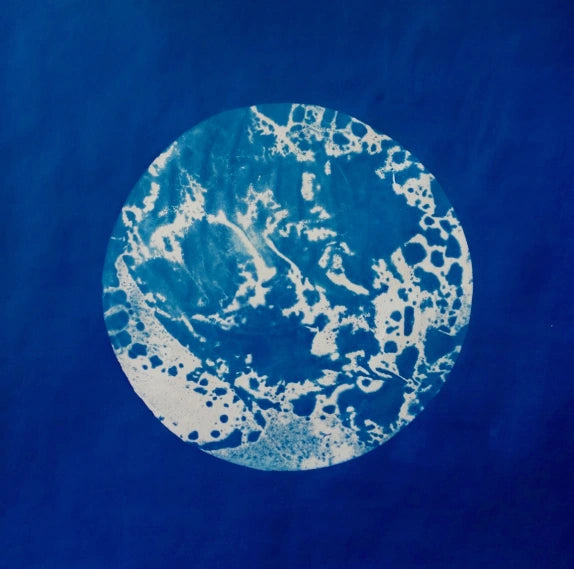 Cyanotype d'une forme ronde texturée, en blanc sur fond bleu de Prusse