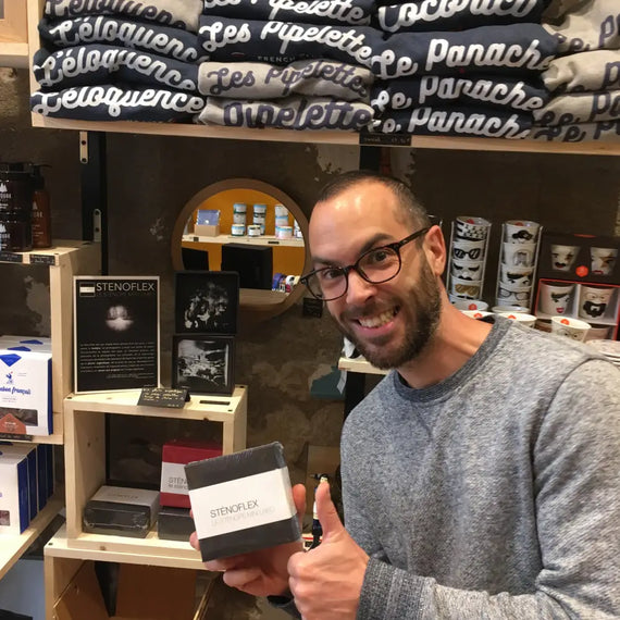 Client satisfait tenant une boîte Sténoflex en boutique