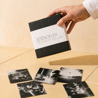 Boîte sténopé Sténoflex noire tenue à la main au-dessus de tirages noir et blanc